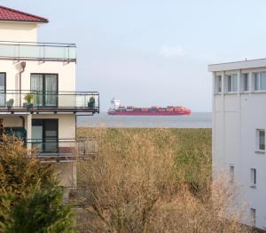 ein Containerschiff im Wasser neben einem Gebäude in der Unterkunft Ferienwohnung mit Meerblick Grimmershörnbucht in Cuxhaven
