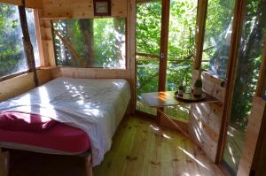 1 dormitorio en una casa del árbol con cama y mesa en ecogite Estien, en Boussenac