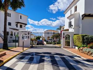 a driveway in front of a white building with a gate at Aldea Blanca Cute in Marbella
