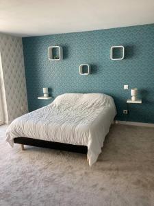 1 dormitorio con 1 cama en una pared azul en Authentique maison en pierre de 160 m2 au calme, en Reignac