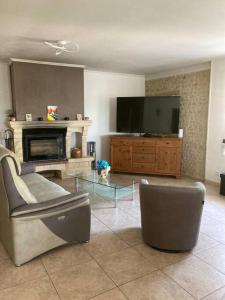 a living room with a couch and a tv at Authentique maison en pierre de 160 m2 au calme in Reignac