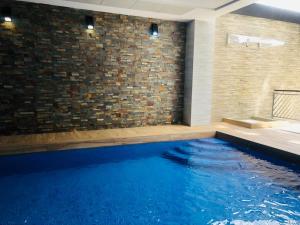 uma piscina com água azul num quarto com uma parede de tijolos em Residencial Alegria 12 em Torrevieja