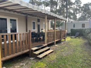 dom z drewnianym tarasem ze stołem w obiekcie MH 3 chambres, camping Les Dunes de Contis, Landes w mieście Saint-Julien-en-Born