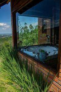 uma casa de banho com uma banheira e uma grande janela de vidro. em Cabana Pedacinho do Céu em Praia Grande