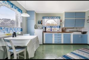 una cocina con armarios azules y una mesa y sillas blancas. en Charming holiday home, en Tromsø