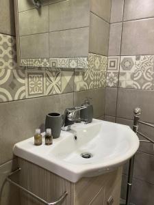 ein Badezimmer mit einem weißen Waschbecken und einem Spiegel in der Unterkunft CLALE ROOMS in Neapel
