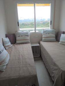 deux lits dans une chambre avec une grande fenêtre dans l'établissement Paraíso, à Miami Platja 27 autres photos