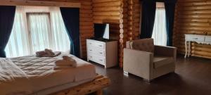 a bedroom with a bed and a chair in a log cabin at Resort Mezini in Ersekë