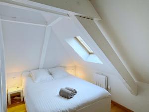 Ce lit blanc se trouve dans un dortoir doté d'une lucarne. dans l'établissement Le Balcon fleuri centre Robertsau tram Jardiniers, à Strasbourg