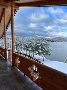 a wooden porch with a view of a snow covered lake at Resort Mezini in Ersekë