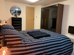 um quarto com uma cama listrada em azul e branco em Apartment in Old Trafford em Manchester