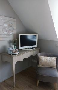 uma secretária com uma televisão e uma cadeira num quarto em Les chambres de l'Atelier em Pont-Aven