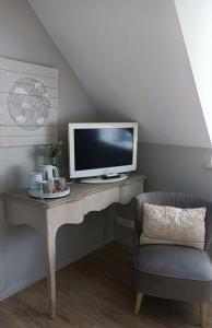 a desk with a tv and a chair in a room at Les chambres de l'Atelier in Pont-Aven