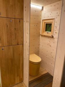 a small bathroom with a toilet in a wooden wall at Zinipi Lodge am Oldtimer auf Demeterhof Michlbauer in Ursensollen