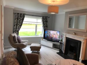 a living room with a television and a fireplace at Fraunhill in Swinford