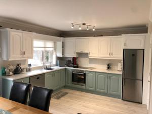 a kitchen with green and white cabinets and a table at Fraunhill in Swinford