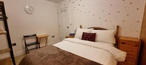 a bedroom with a bed and a chair and a clock at GOLD Penthouse Room 5min to Basingstoke Hospital in Basingstoke