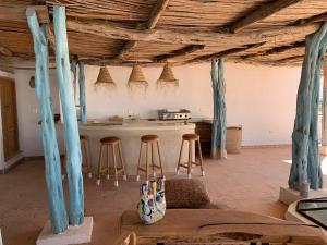 una cocina con techos de madera y una barra con taburetes en Dar Gecko, en Sidi Kaouki