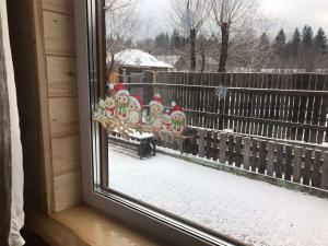 a window with christmas decorations on a bench in the snow at Kostel House in Mykulychyn
