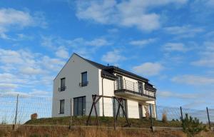 a white house on a hill with a fence at Słoneczny Zakątek Sominy in Sominy