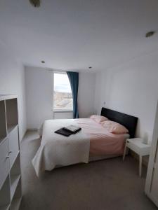 ein weißes Schlafzimmer mit einem Bett und einem Fenster in der Unterkunft Spacious & Serene Stay in London in Forest Hill
