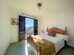 um quarto com uma cama e uma grande janela em BnS - Casa La Prensa - Alpujarra em Sorvilán