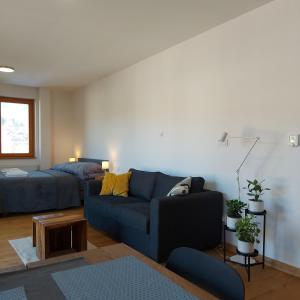 a living room with a blue couch and a bed at Apartman 22, Rezidence & Wellness Javor in Železná Ruda