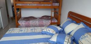 a bedroom with two bunk beds with blue and white pillows at Aconchegante apartamento com vista para o mar -Guilhermina in Praia Grande