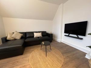 a living room with a black couch and a flat screen tv at Ferienwohnung in Bad Bramstedt in Bad Bramstedt