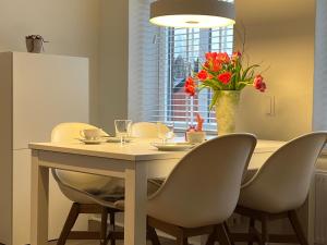 a dining room table with chairs and a vase with red flowers at Ferienwohnung in Bad Bramstedt in Bad Bramstedt