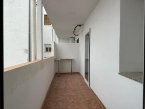un couloir avec des murs blancs, une table et des fenêtres dans l'établissement Alamos Suite, à Jaén