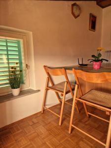 comedor con 2 sillas, mesa y ventana en House among olive trees with a sea view 1, en Ankaran