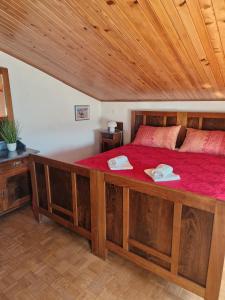 Un dormitorio con una gran cama de madera con sábanas rojas. en House among olive trees with a sea view 1, en Ankaran