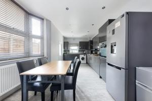 a kitchen with a table and chairs and a refrigerator at Cozy 4 bedroom home in Hackney, London in London