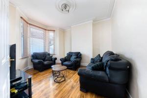 a living room with two couches and a tv at Cozy 4 bedroom home in Hackney, London in London