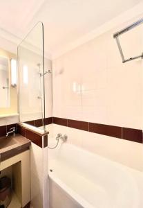 La salle de bains blanche est pourvue d'une baignoire et d'une douche. dans l'établissement CAP ESTEREL AGAY SAINT RAPHAEL VUE MER Studio 4 personnes chez Evelyne, à Saint-Raphaël