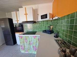 a kitchen with green tiles and a white counter top at Villa MARICO in Ducos