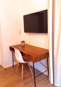 Elle comprend un bureau en bois avec une chaise et une télévision murale. dans l'établissement Apartment Emilie with parking historic city center, à Merano