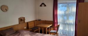 ein Schlafzimmer mit einem Bett, einem Tisch und einer Uhr in der Unterkunft 2 Zimmer Mitterdorf in Philippsreut