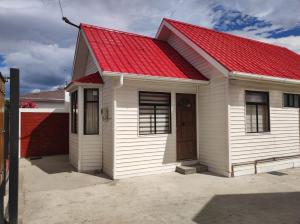 a small white house with a red roof at TyP Departamentos in Puerto Natales