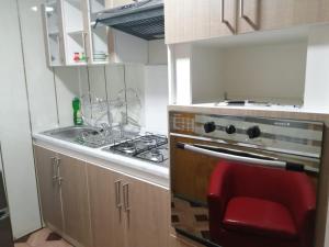 a kitchen with a stove and a sink and a red chair at TyP Departamentos in Puerto Natales