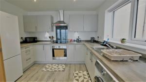 a kitchen with white cabinets and a sink at Lovely New 2 Bedroom Condo with Stunning Seaviews in Penmaen-mawr