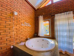 a bathroom with a large tub in a brick wall at Chalé Jacarandá - Hidro - Wifi e mais in Sapucaí-Mirim