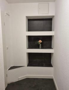 ein Zimmer mit weißen Regalen mit einer Vase mit einer Blume in der Unterkunft Ferienwohnung Nähe Hbf Bremerhaven in Bremerhaven