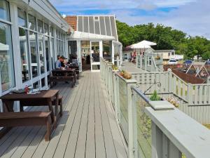 una terraza de madera con bancos y mesas en un edificio en luxury new 3 bed caravan with stunning sea view on private beach in Thorness bay, en Porchfield