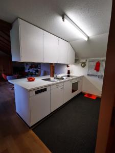 una cocina con armarios blancos y fregadero en Marmottin en Lucerna