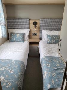 a bedroom with two beds and a table with a lamp at luxury new 3 bed caravan with stunning sea view on private beach in Thorness bay in Porchfield