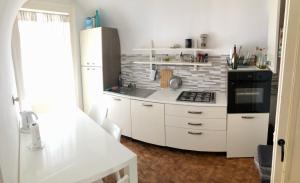 eine Küche mit weißen Schränken und einem schwarzen Herd mit Backofen in der Unterkunft Ambra House in Catania