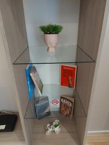 une étagère avec des livres et une plante en pot dans l'établissement White grapes apartment, à Petrich