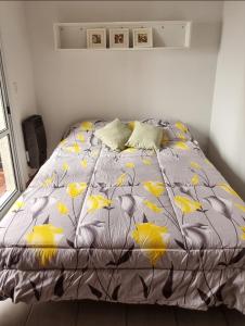 Una cama con un edredón gris con hojas amarillas. en DEPARTAMENTO AGOTE en Mendoza